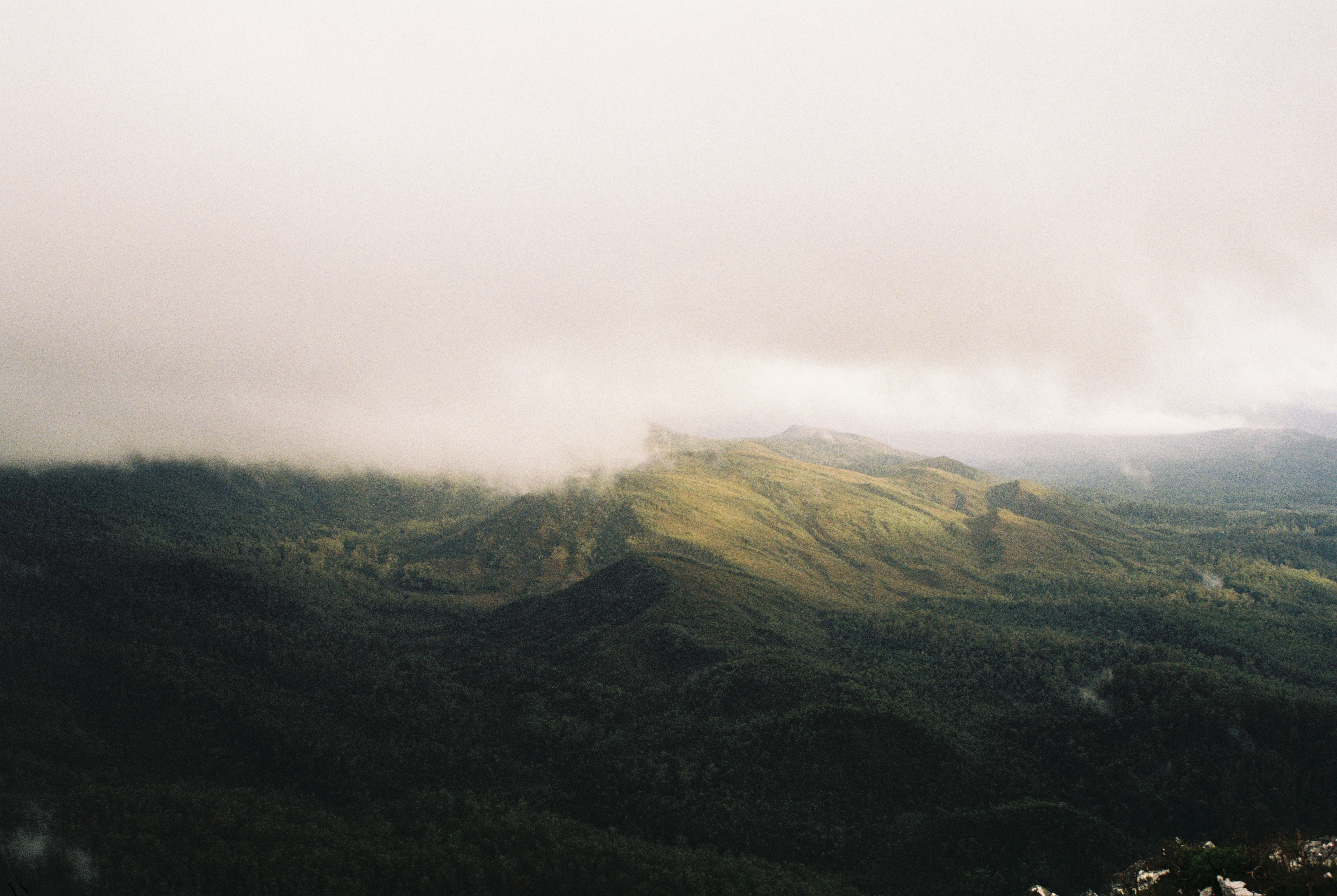 Mountains with sun peeking through clouds.