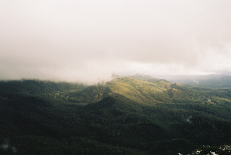 Mountains with sun peeking through clouds.
