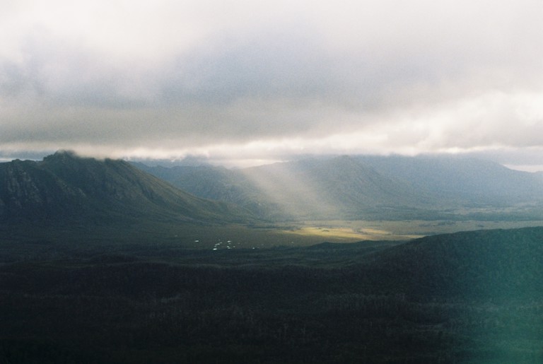 Mountains with sun peeking through clouds.
